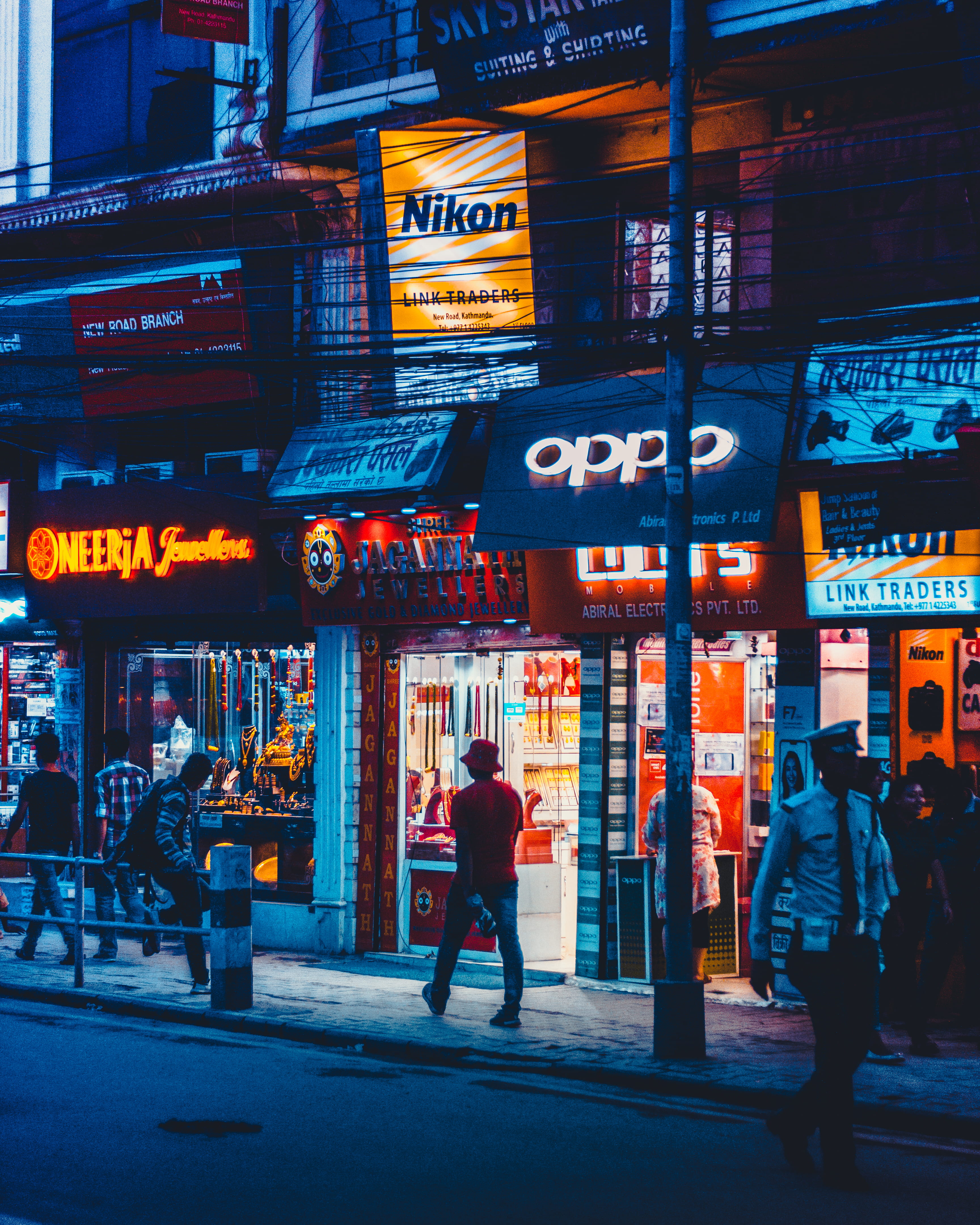 man walking beside OPPO front store, person, neon, canon, nepal