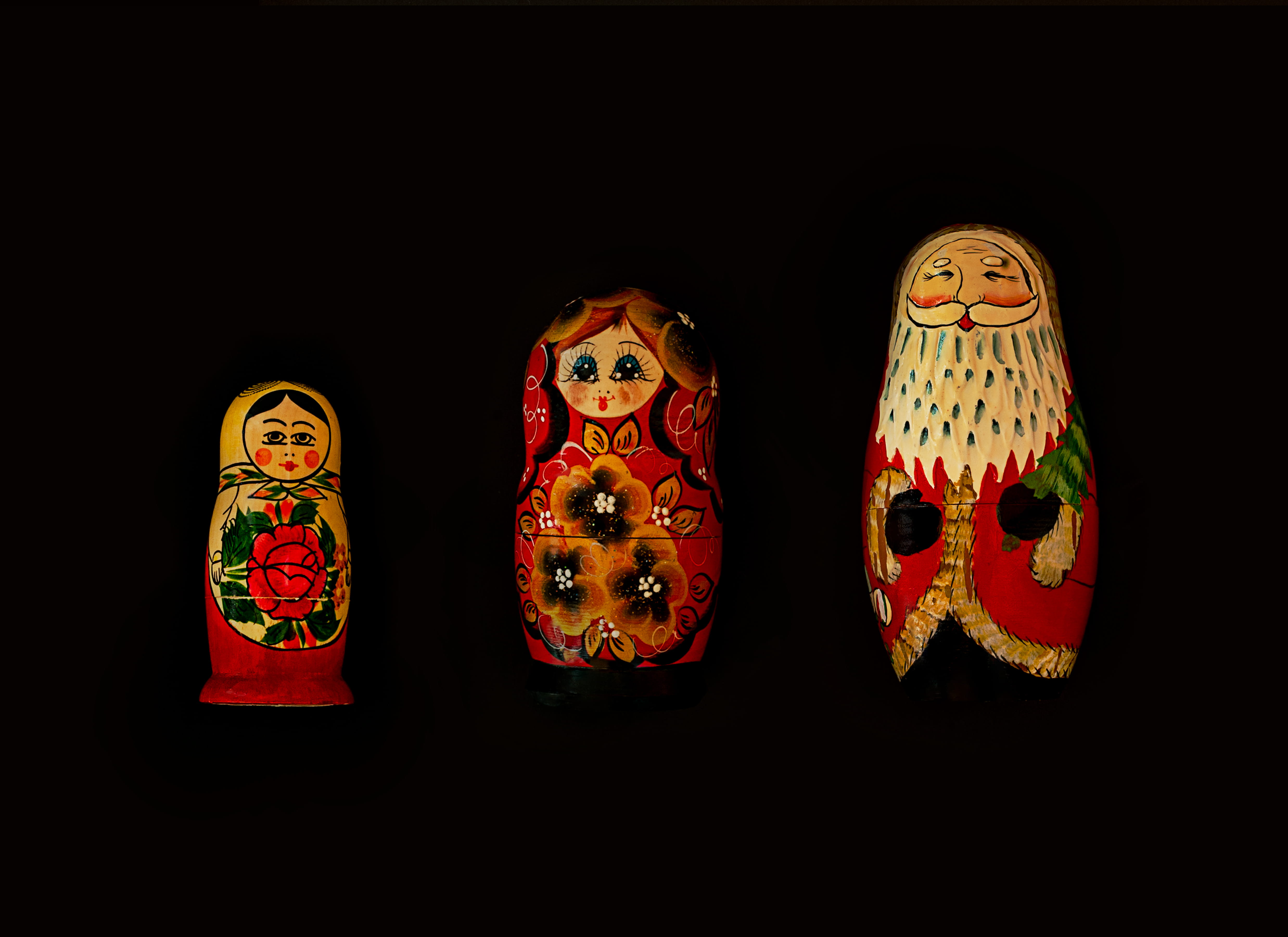 three assorted-color nesting dolls, black background, art and craft