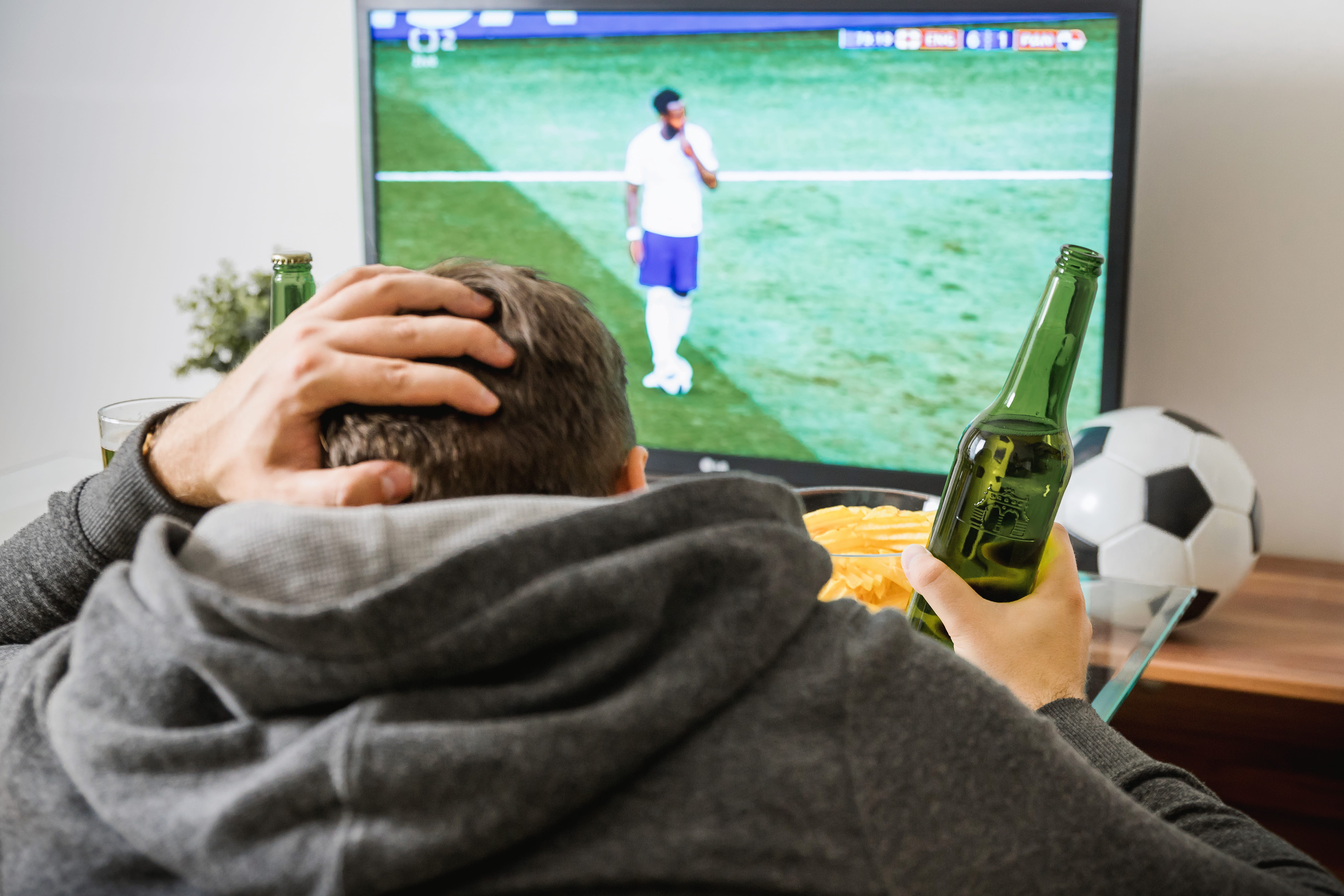 Young man watching football sport on tv at home., soccer, team sport