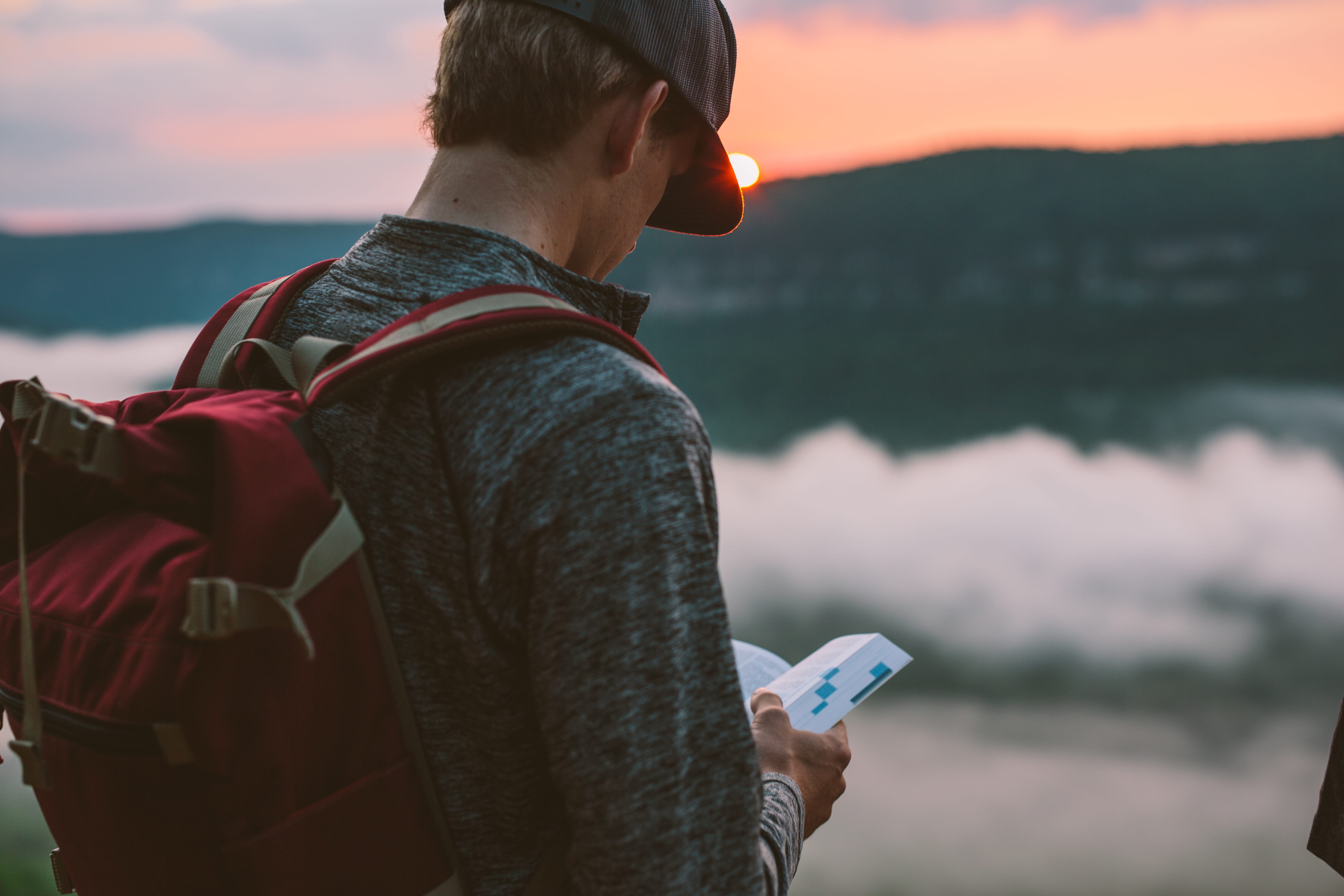 man using a map, mountain, sunset, book, view, explore, backpack