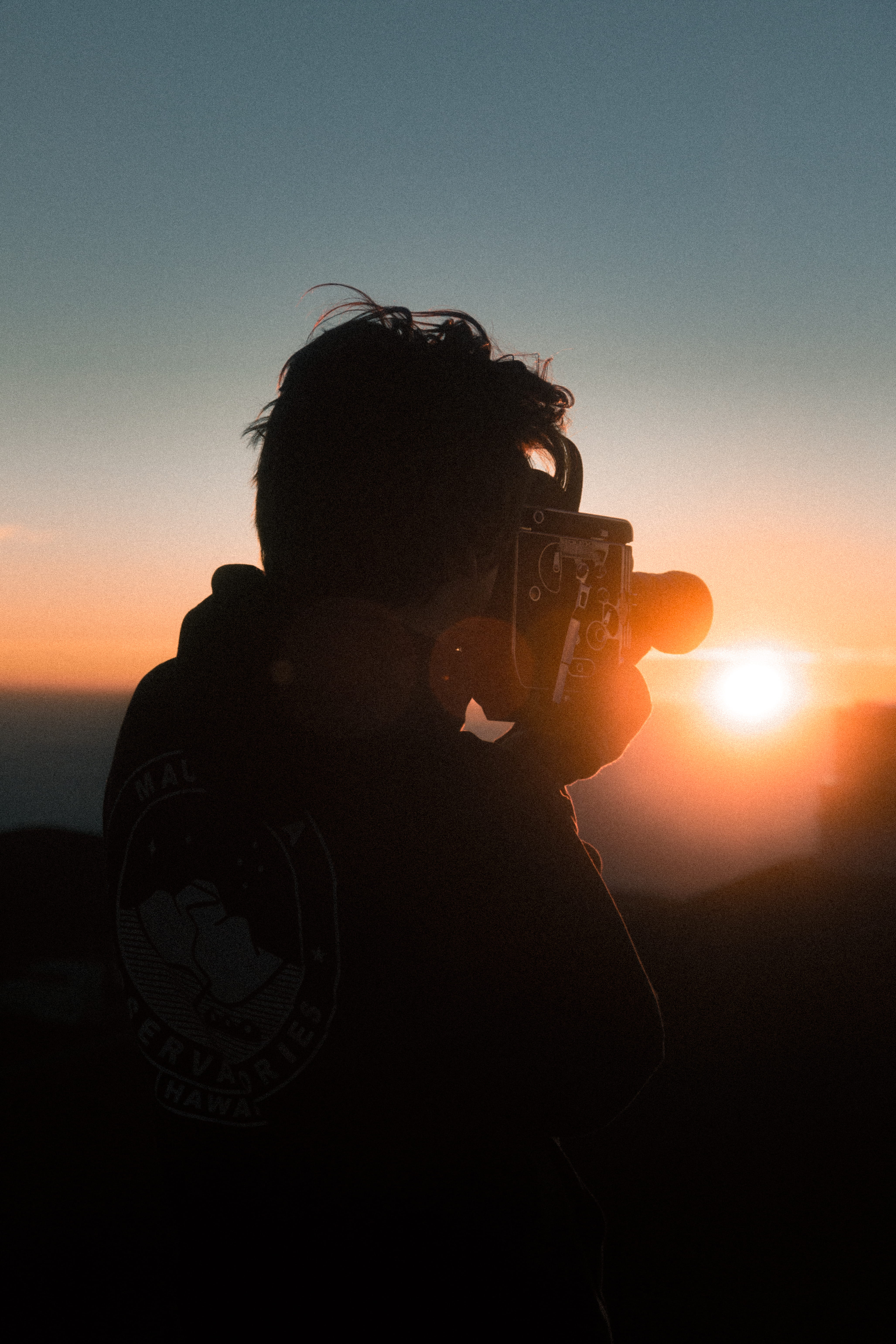 man holding classic camera during golden hour, sun, person, nature