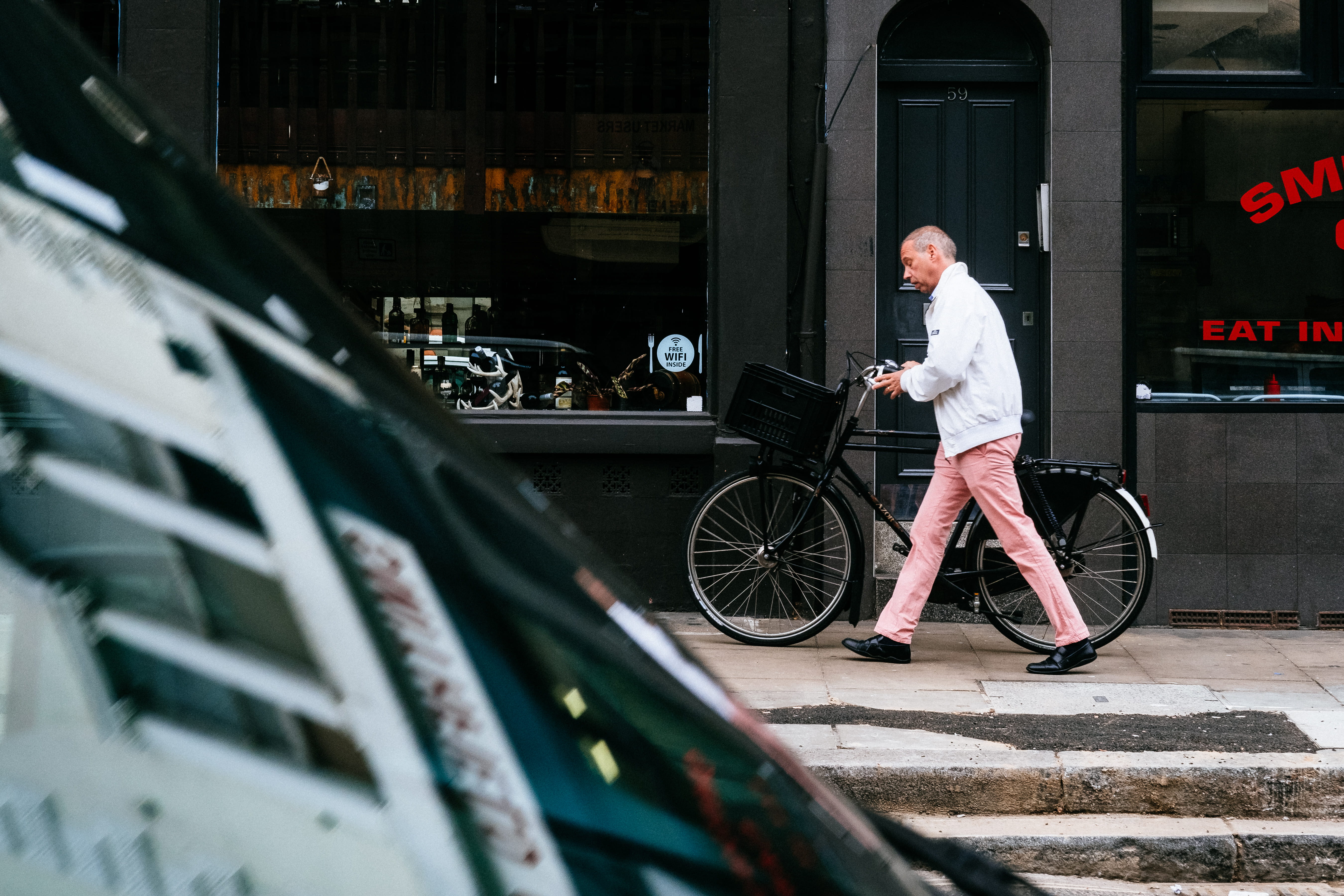 man walking beside bicycle, person, street, city, bike, storefront