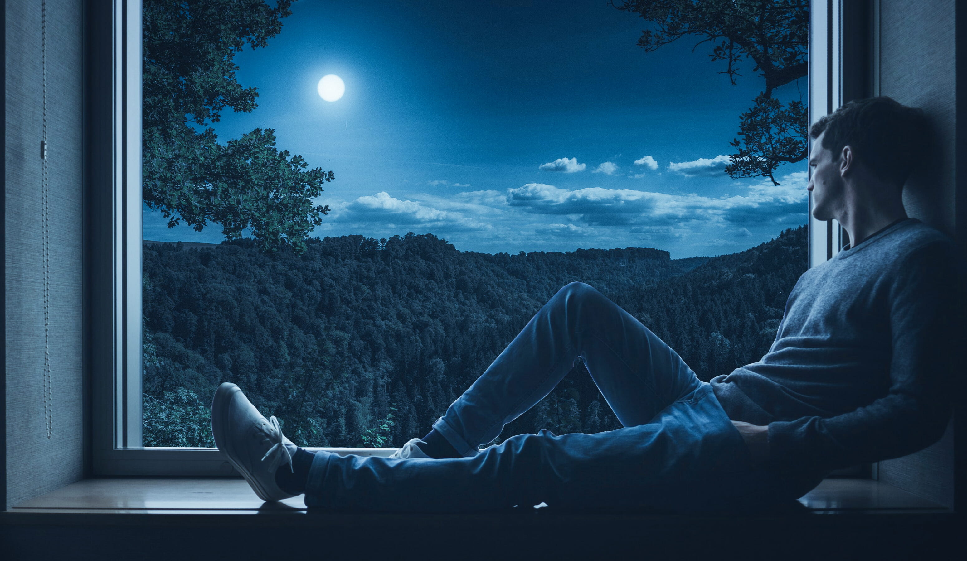 Man sitting on a window sill, looking out at night, person, solo