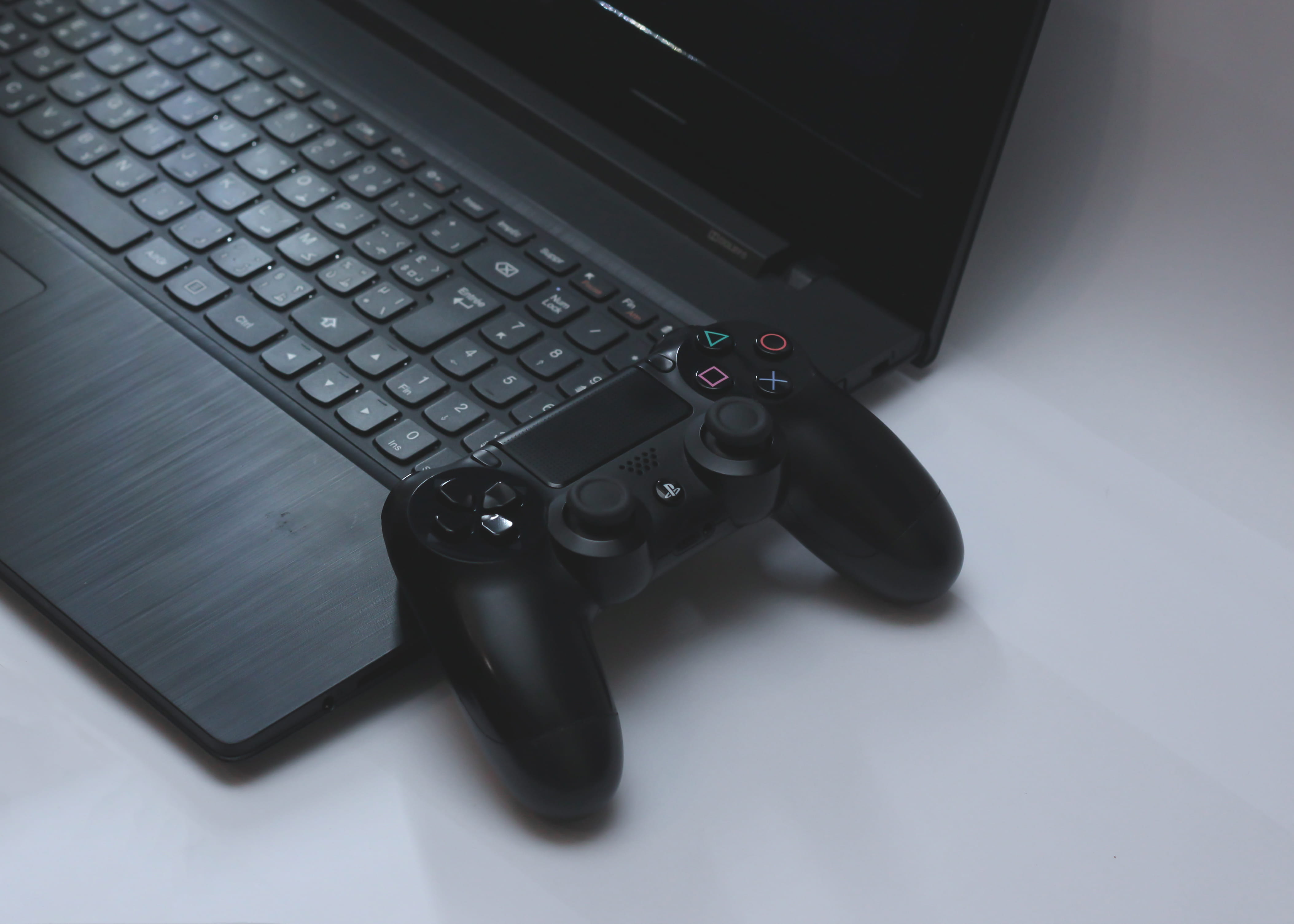 black Sony DualShock 4 controller on black laptop computer, electronics