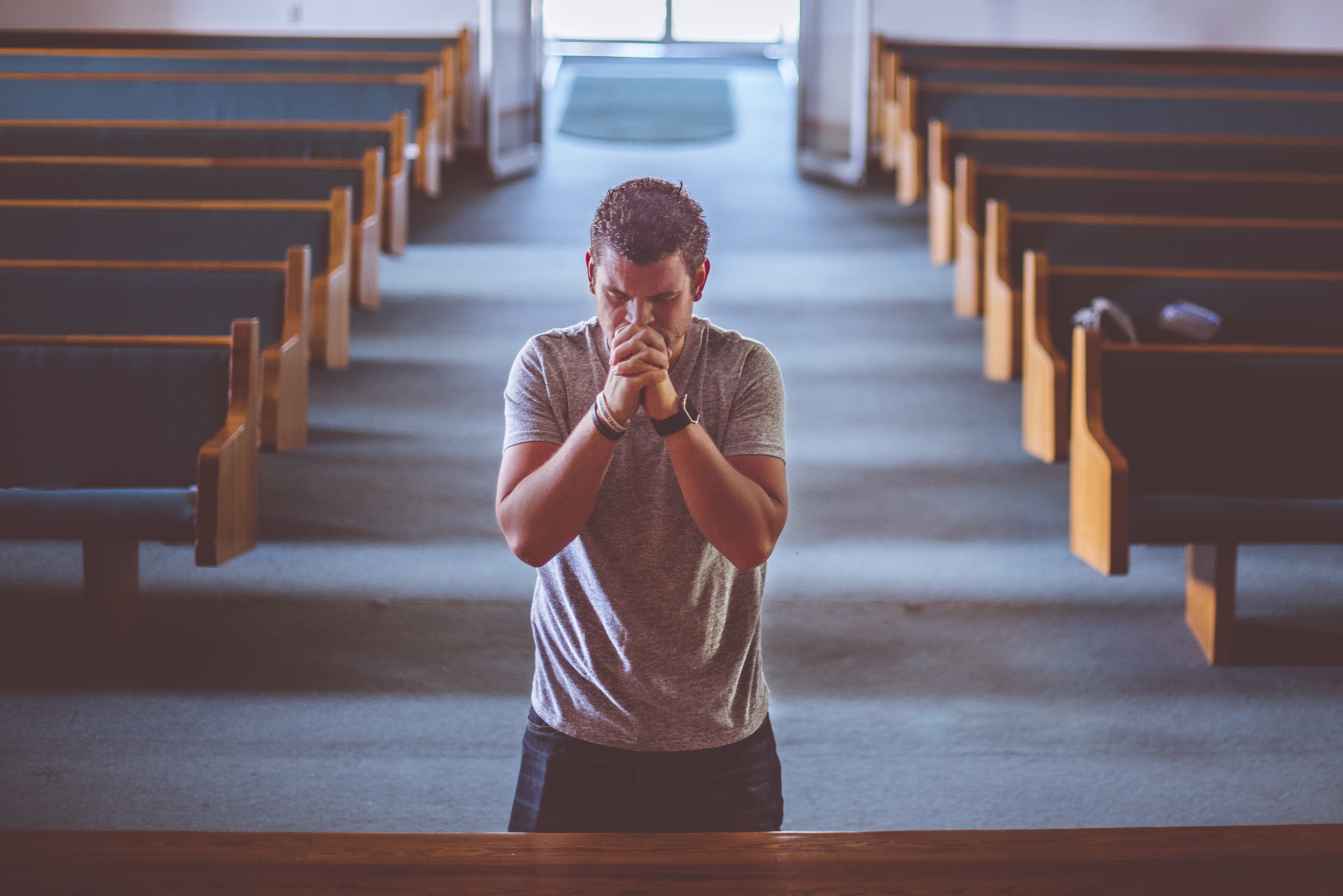 A man praying in a church., one person, casual clothing, indoors
