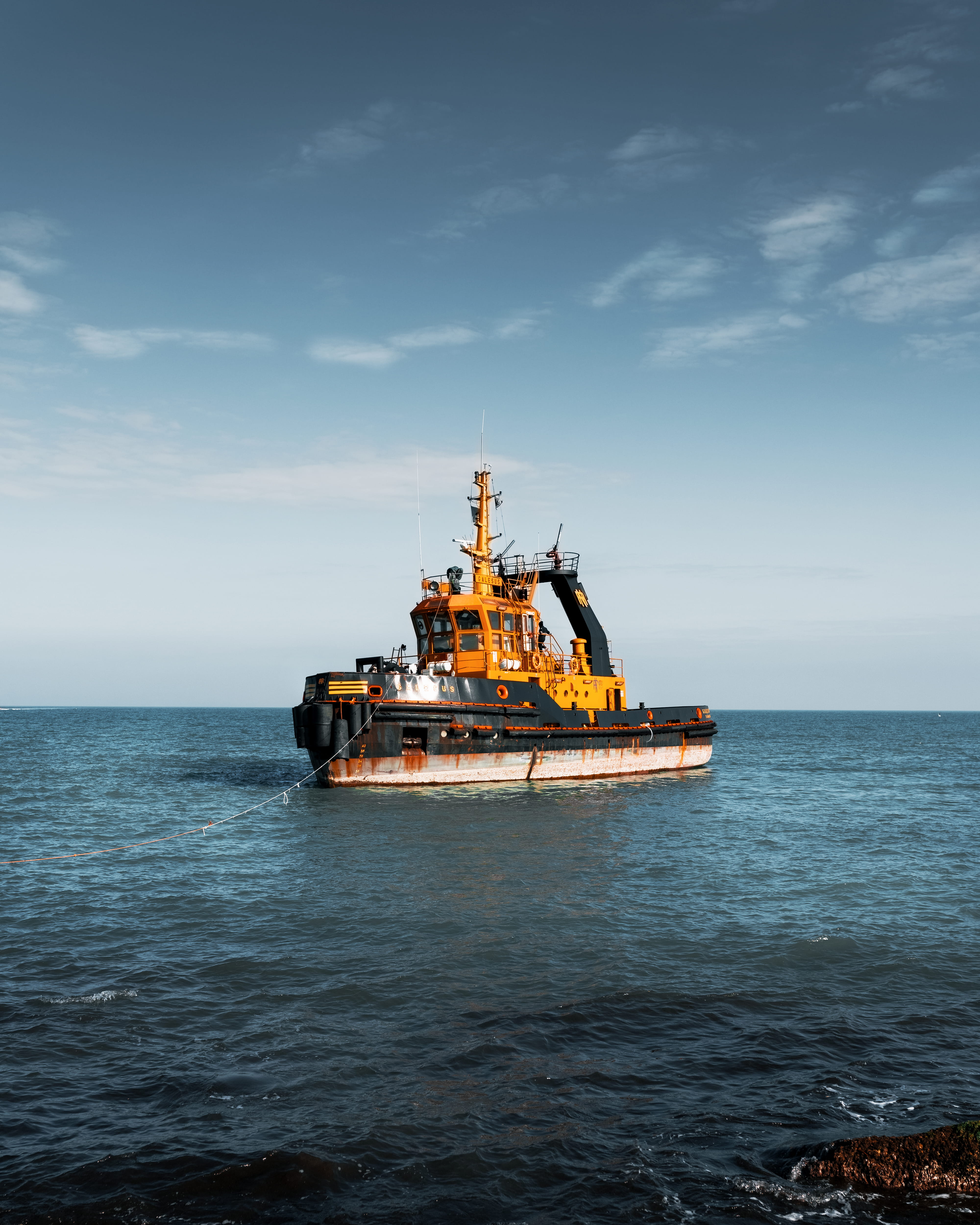 black-and-yellow tugboat on calm water during daytime, vehicle