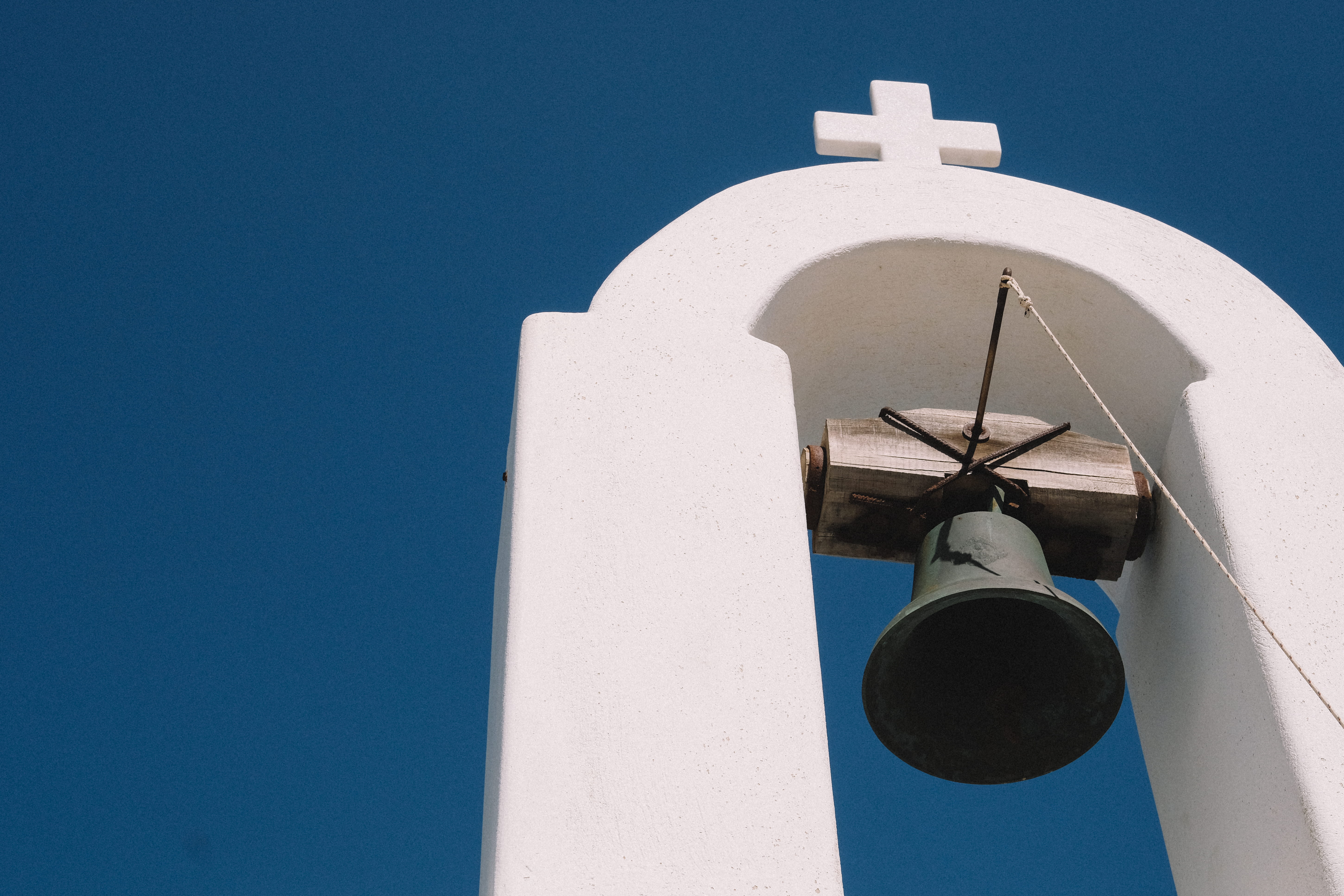 gray bell hanging on white arch, blue, tower, built structure