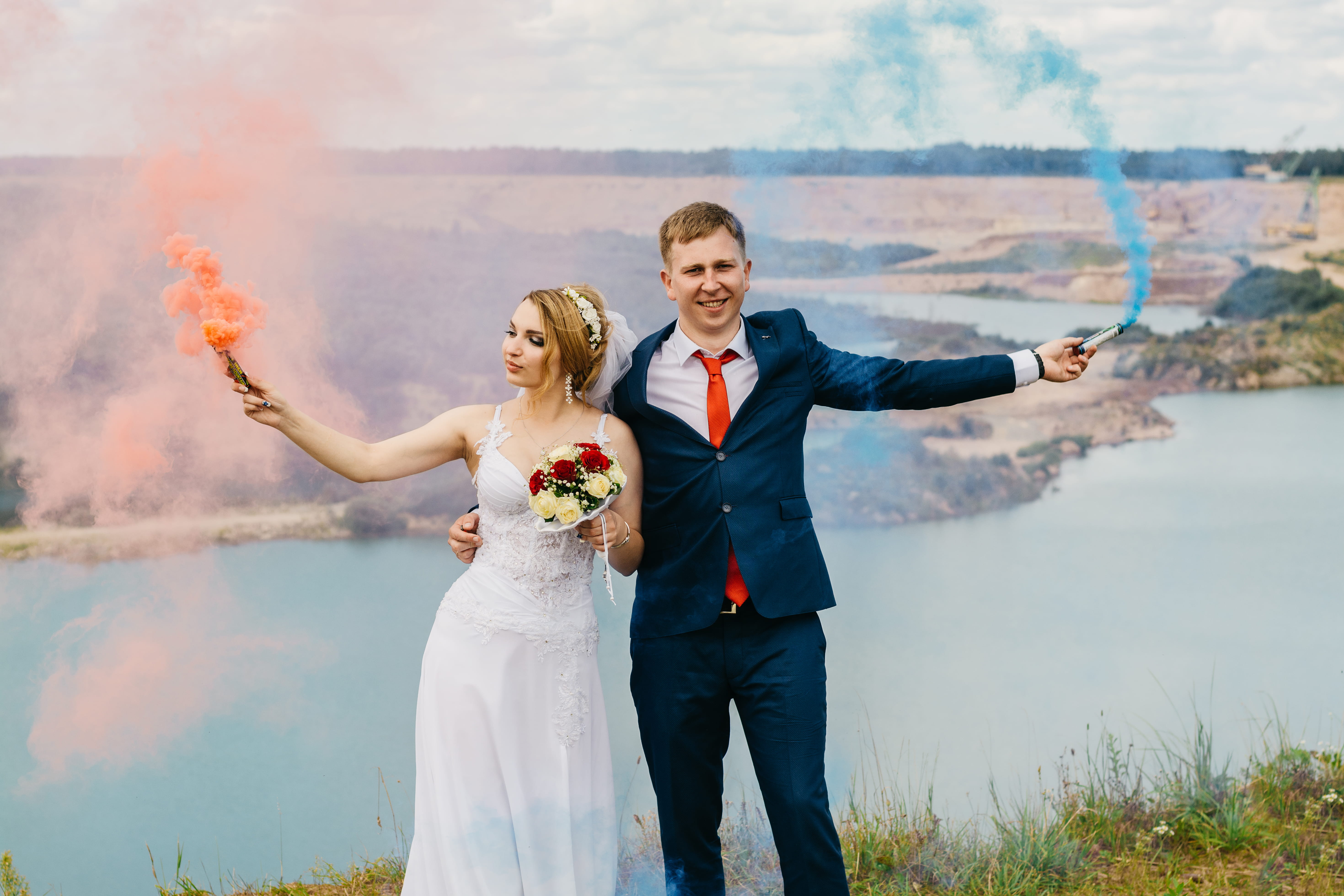 Bride And Groom Holding Smoke Bombs Near Body Of Water, beautiful