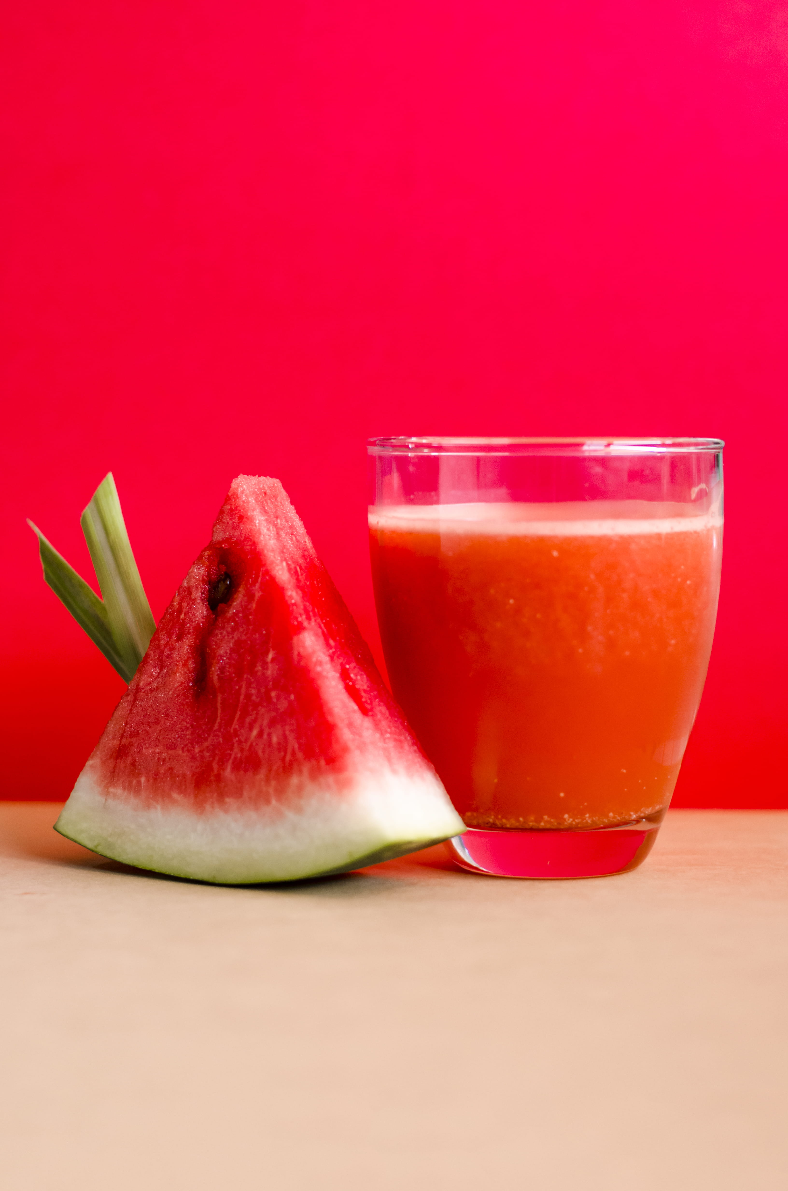 Watermelon Shake Filled Glass Cup Beside Sliced Watermelon Fruit on Brown Surface