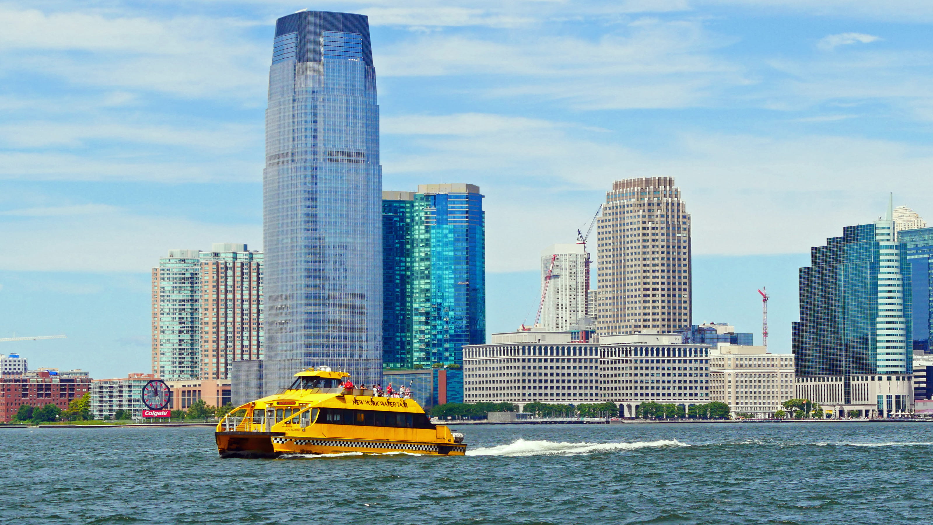 A yellow New York Water Taxi cruises pass Jersry City waterfront on the Hudson River out toward New York Harbor for a siteseeing cruise.