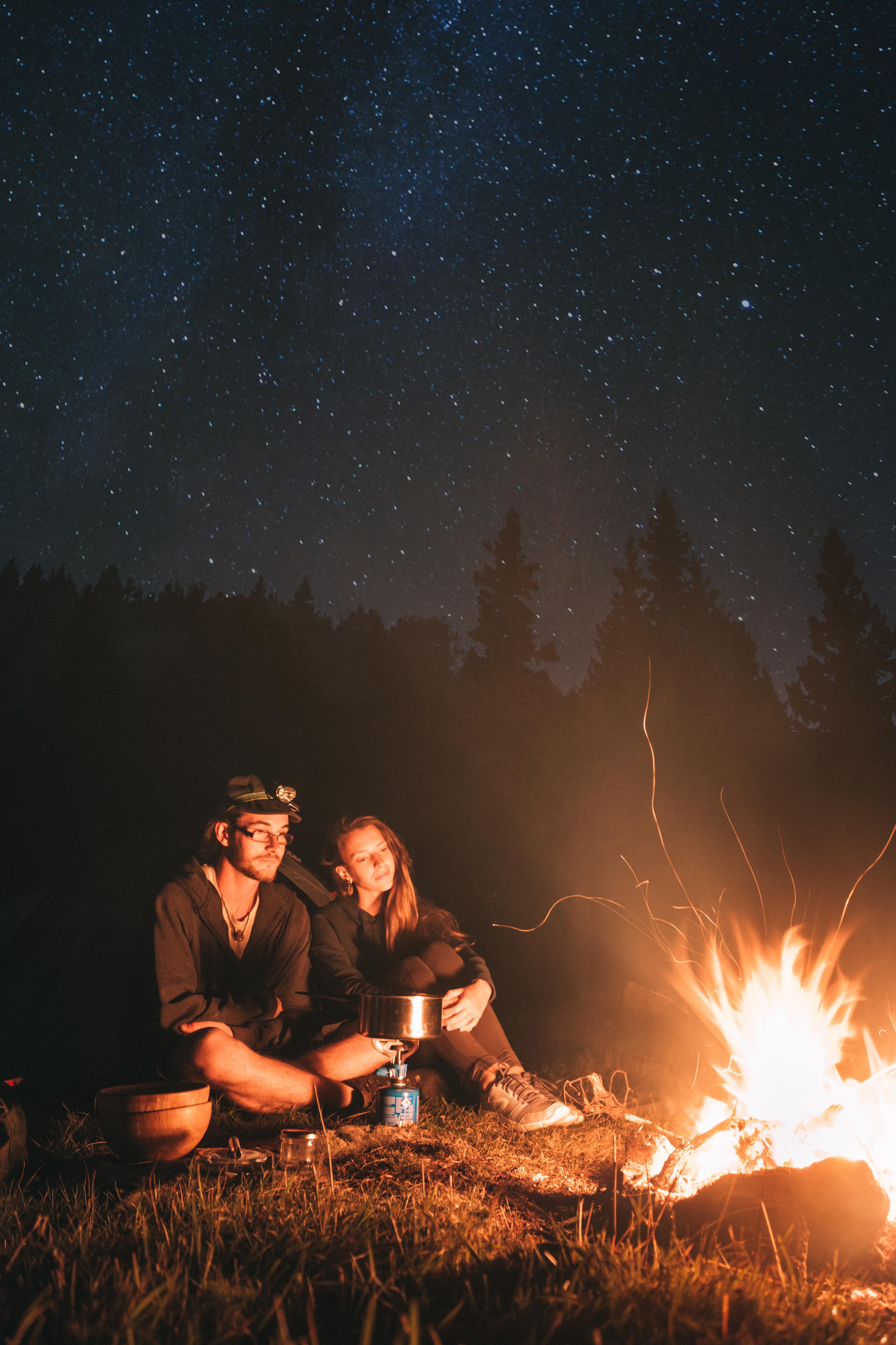 couple sitting near bonfire, man, woman, pot, flame, night, evening