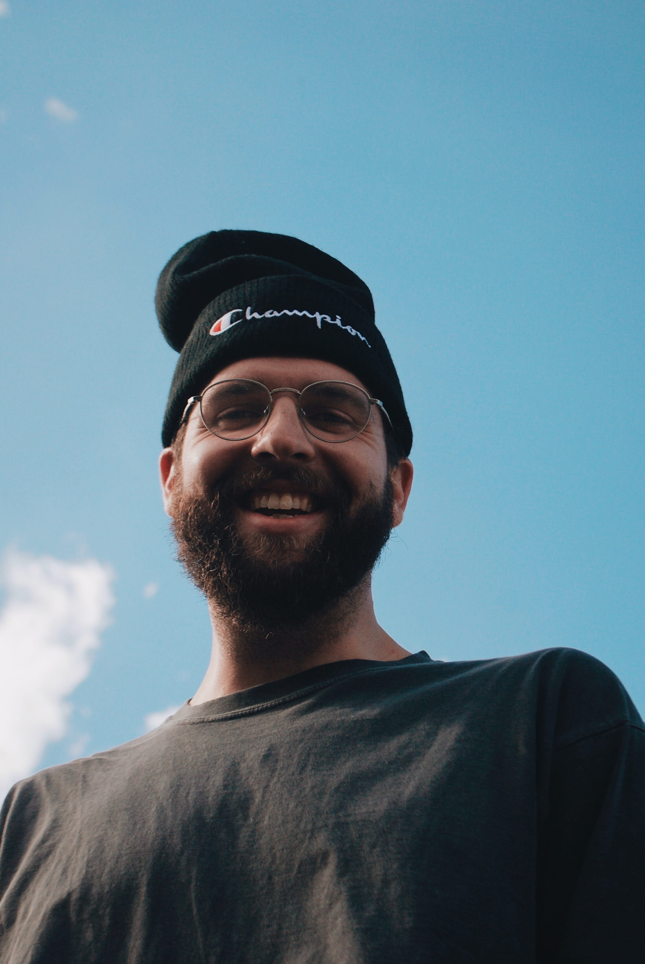 man smiling while looking down, sky, portrait, low angle view