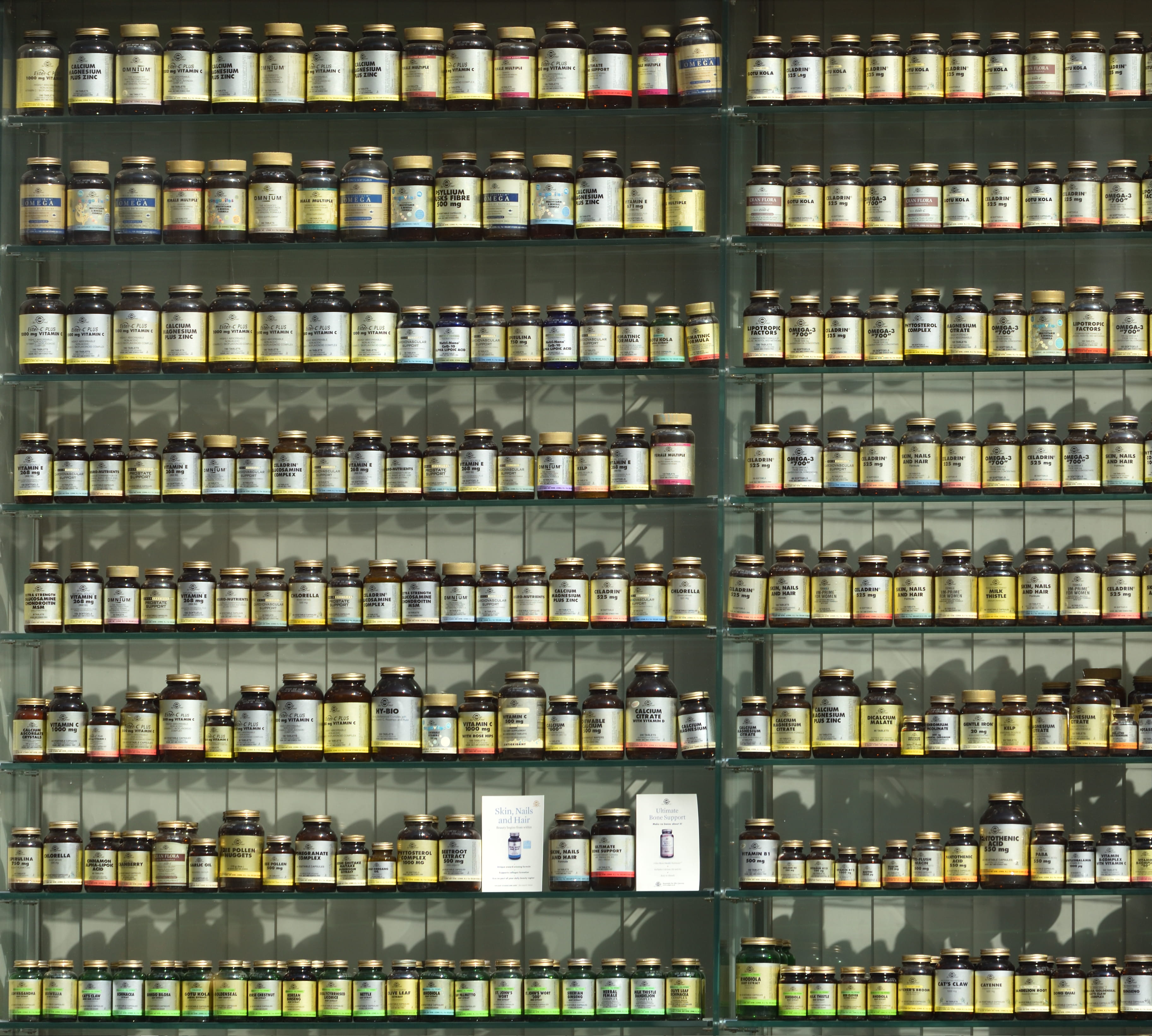 assorted labeled bottle on display shelf, large group of objects
