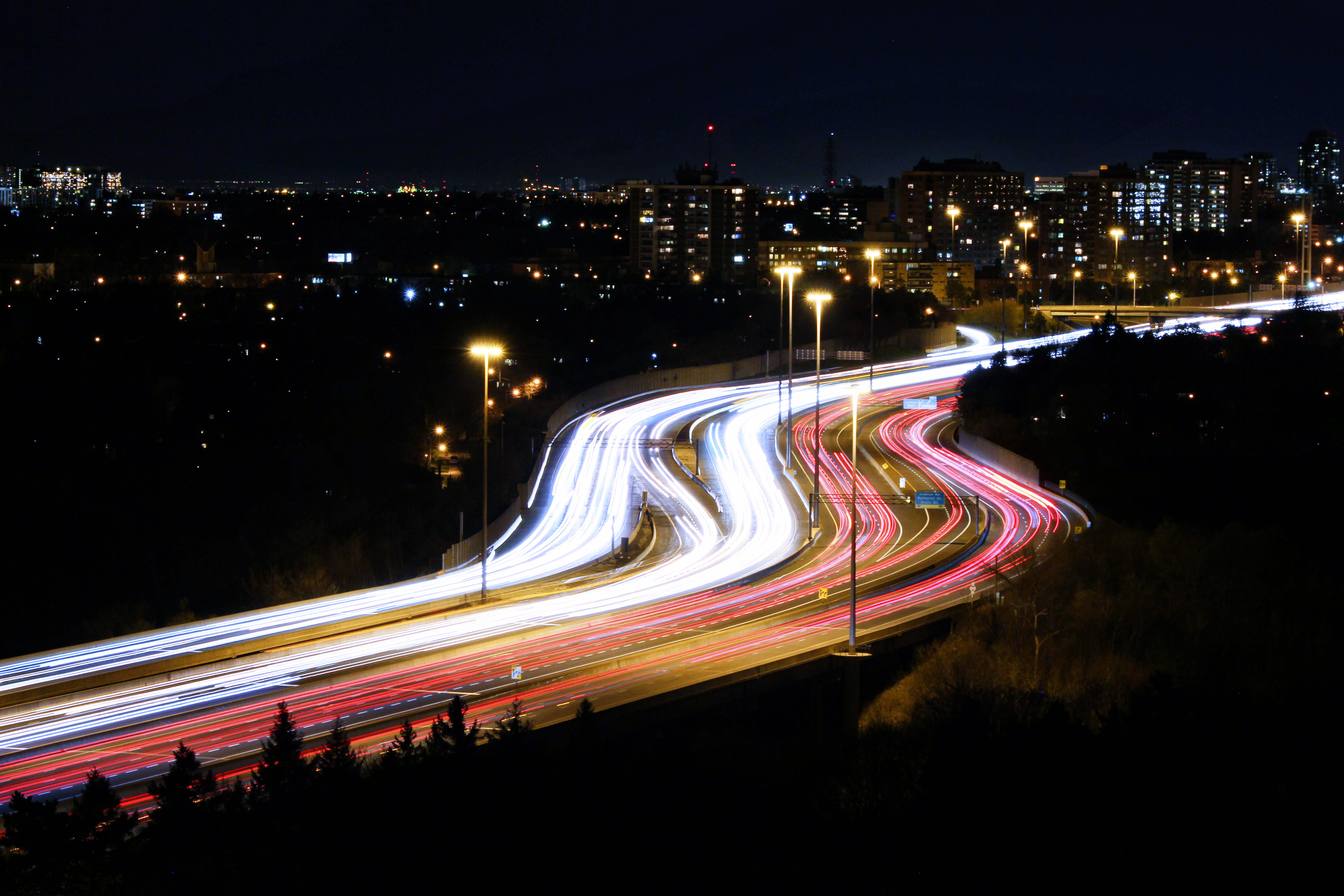 time lapse photography of street lights on road in between building during night time