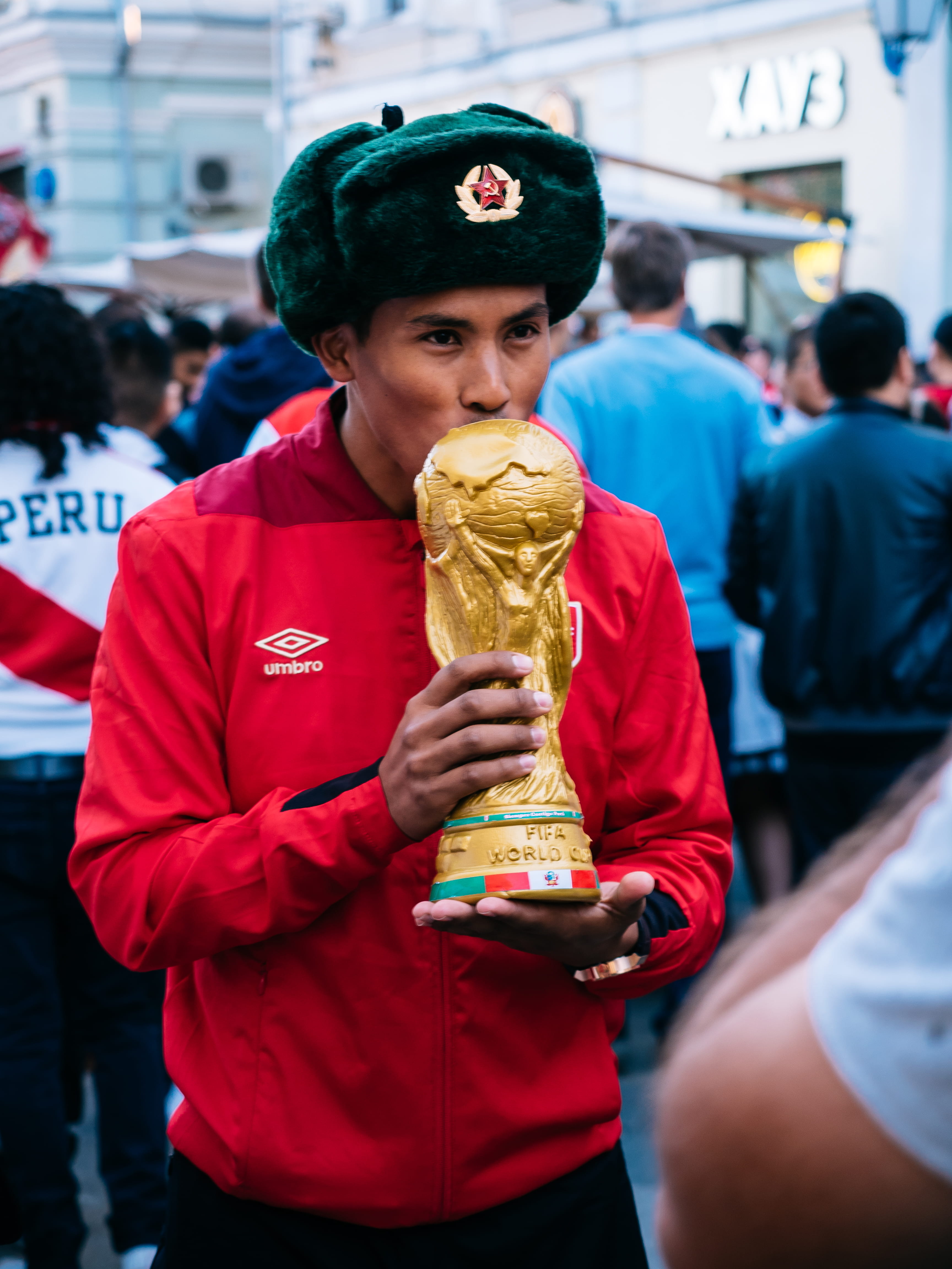 man holding FIFA World Cup trophy, real people, incidental people