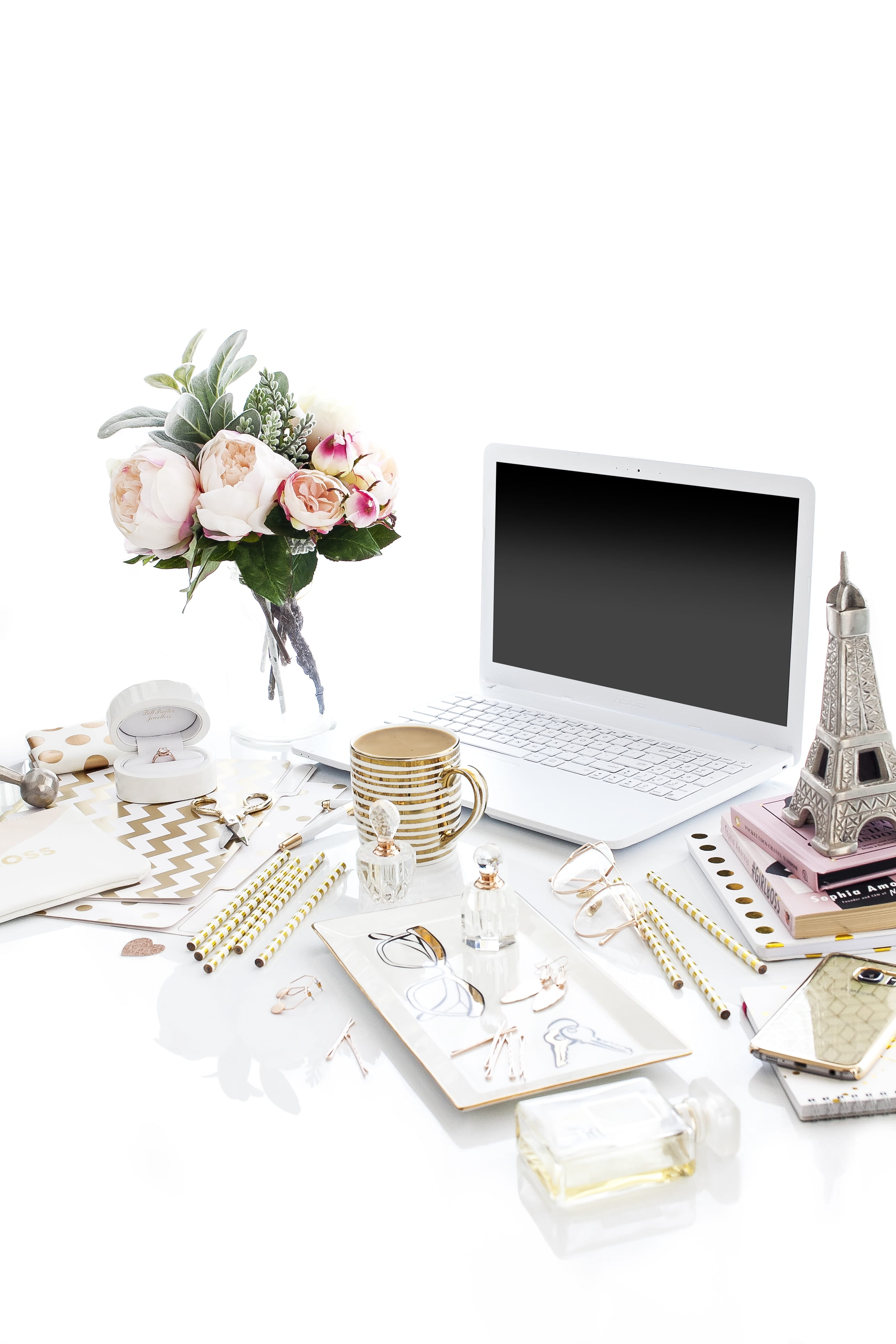 laptop computer surrounded by assorted items, flowering plant