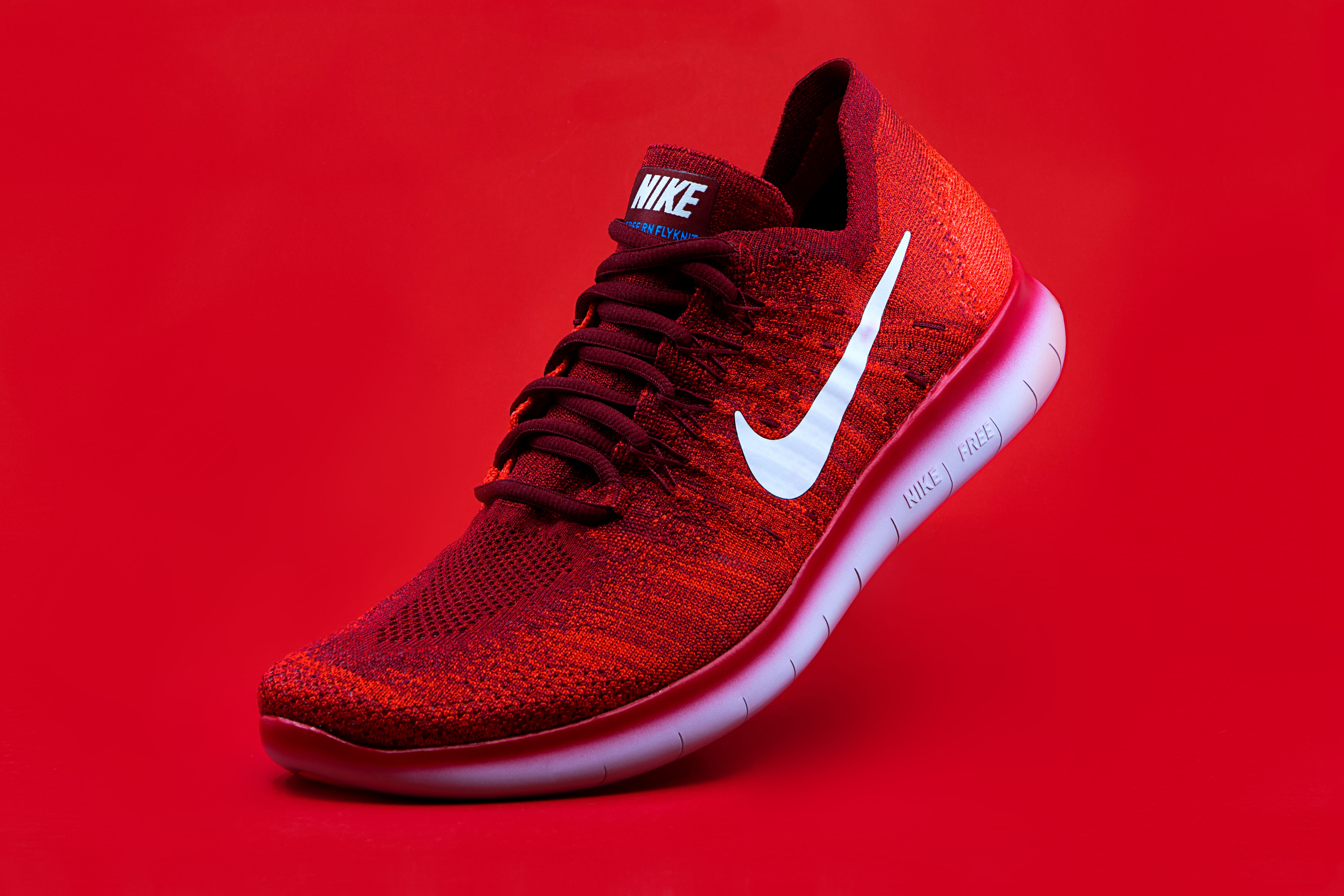 unpaired red Nike sneaker, shoe, fashion, studio shot, colored background