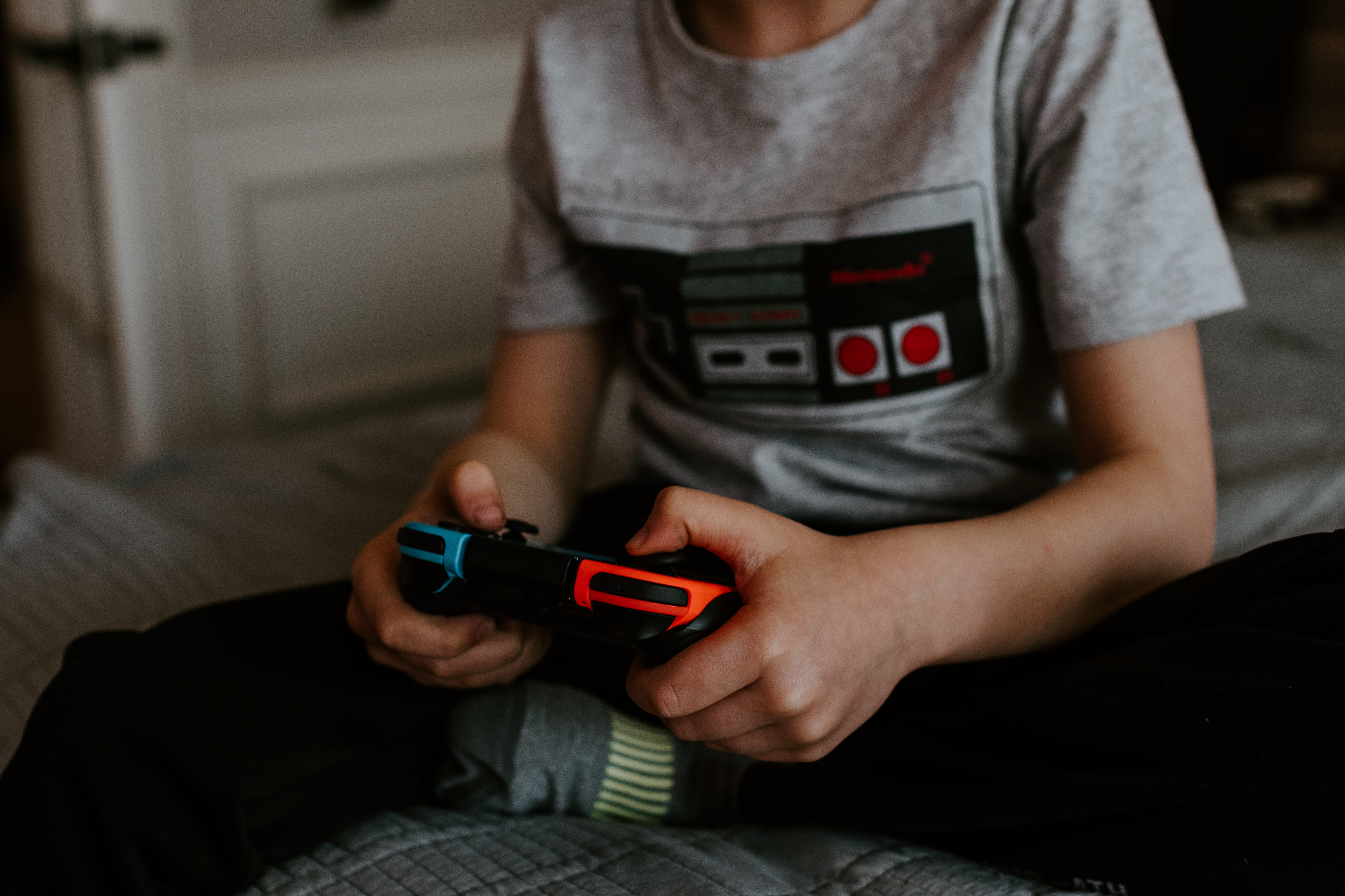 kid sitting on gray bed while playing, holding, technology, midsection