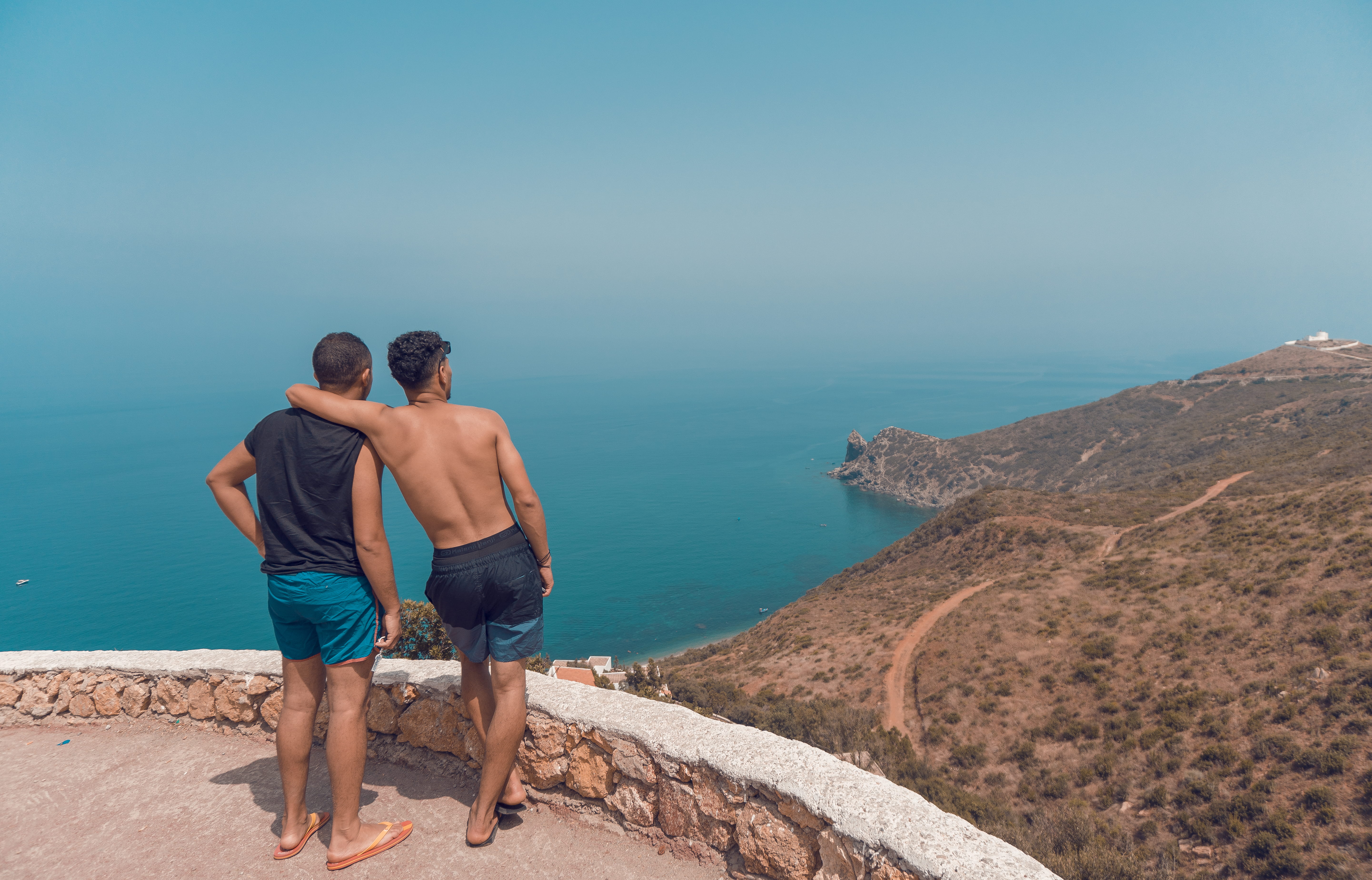 Two Man Standing on Mountain Cliff With Ocean View, back view