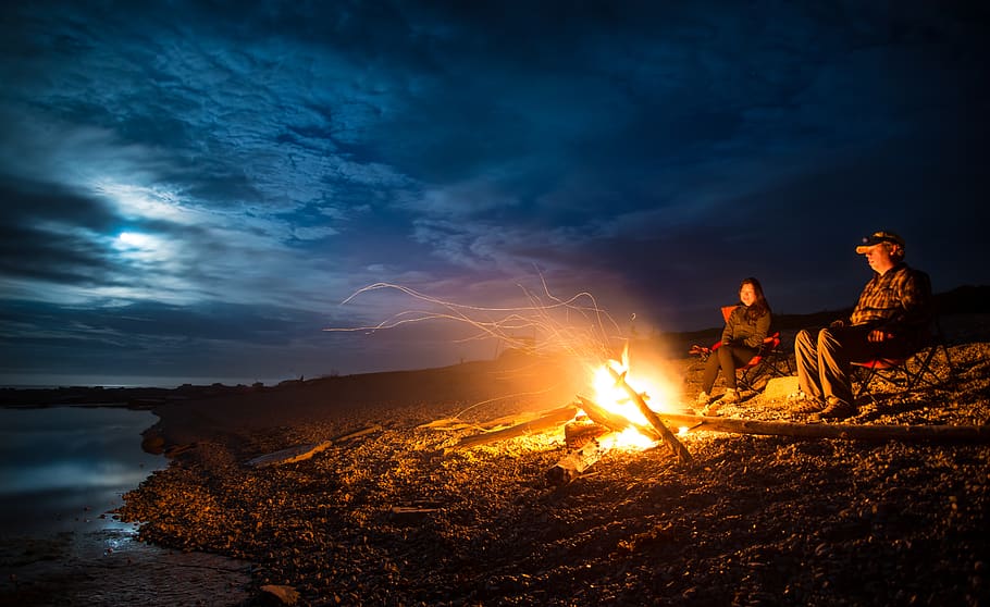 man and woman standing near bonfire on seashore during night, HD wallpaper