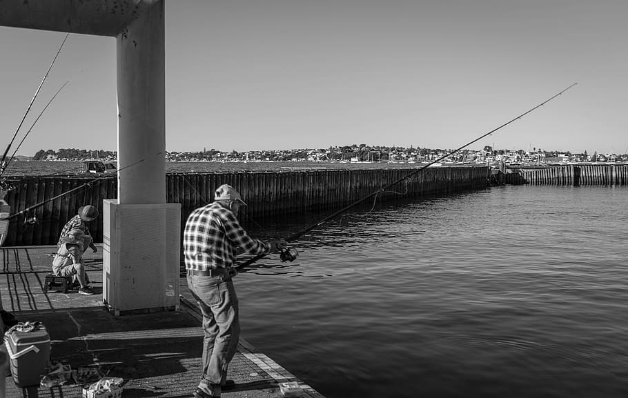 grayscale photography of people fishing on body of water, person
