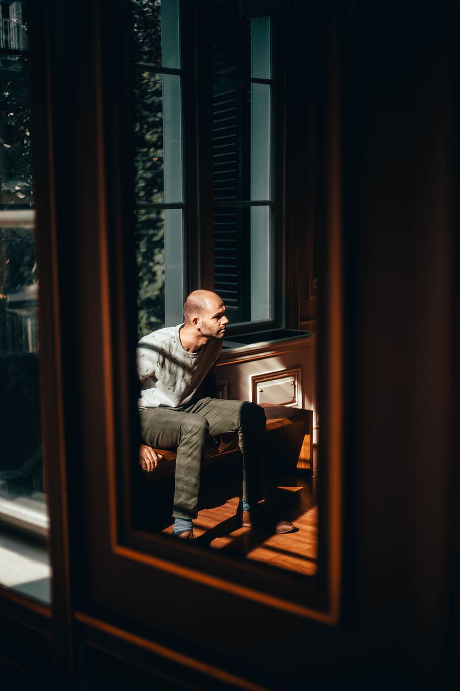 man sitting against window near mirror, reflection, light, person