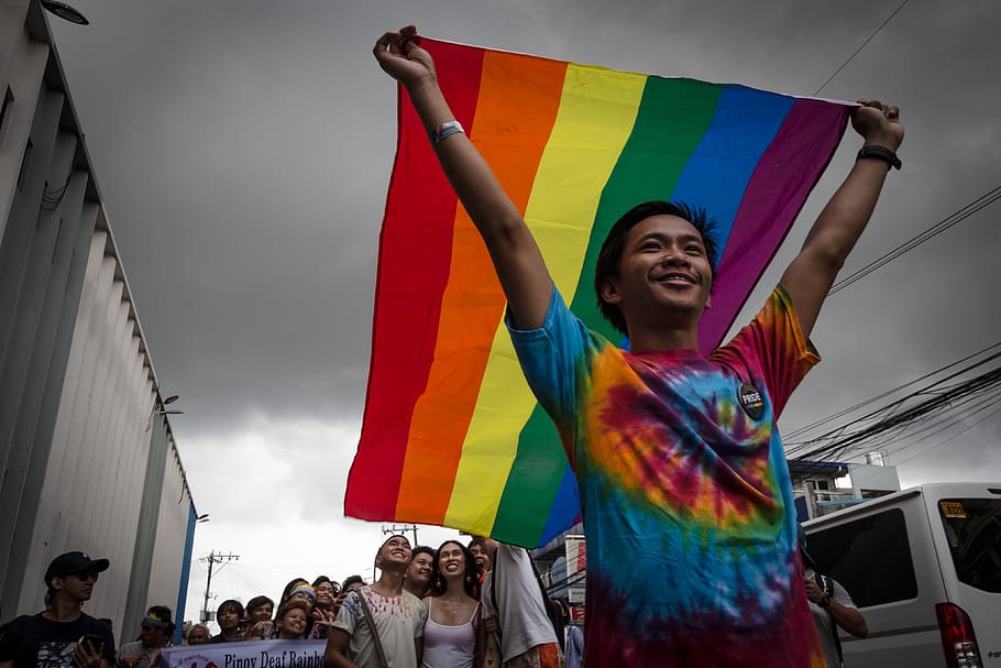 man holding LGBT flag, multi colored, happiness, emotion, real people