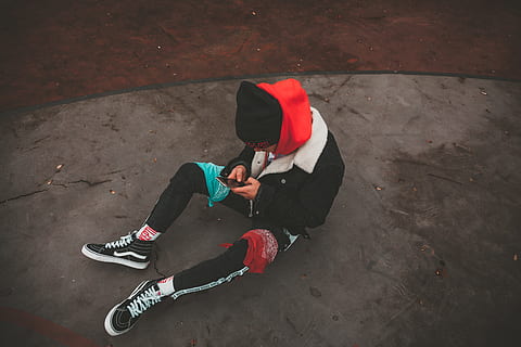 man sitting on grey pavement using smartphone, clothing, apparel HD wallpaper