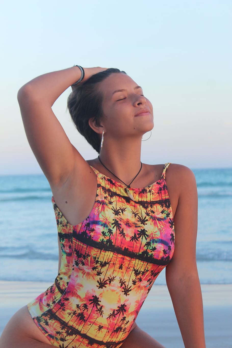 Photo of Woman in Multicolored One-piece Swimsuit Posing With Her Eyes Closed