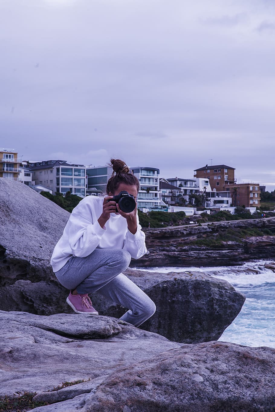 Woman Sitting on Rock While Taking Photo, beach, buildings, camera HD wallpaper