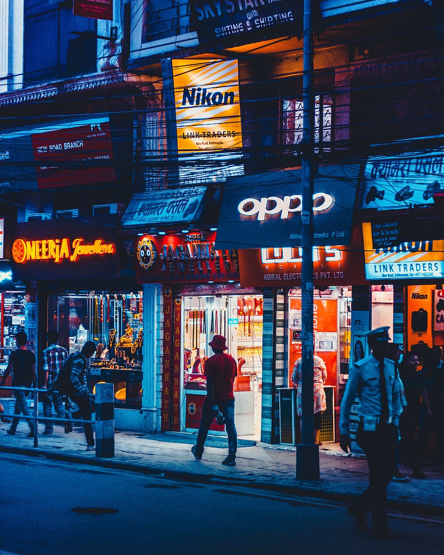 man walking beside OPPO front store, person, neon, canon, nepal