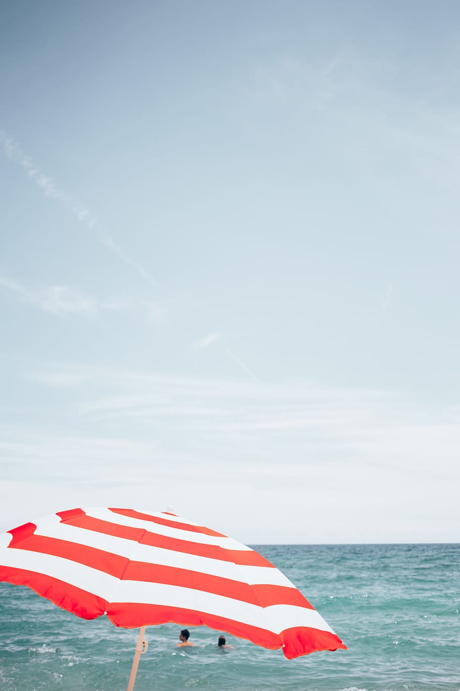 A beach umbrella with people swimming in the background, Bay HD wallpaper