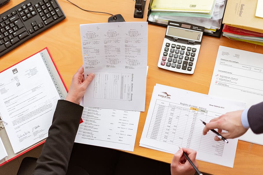 Person Holding Paper in Left Hand and Pen on Right Hand Sitting Beside Desk HD wallpaper
