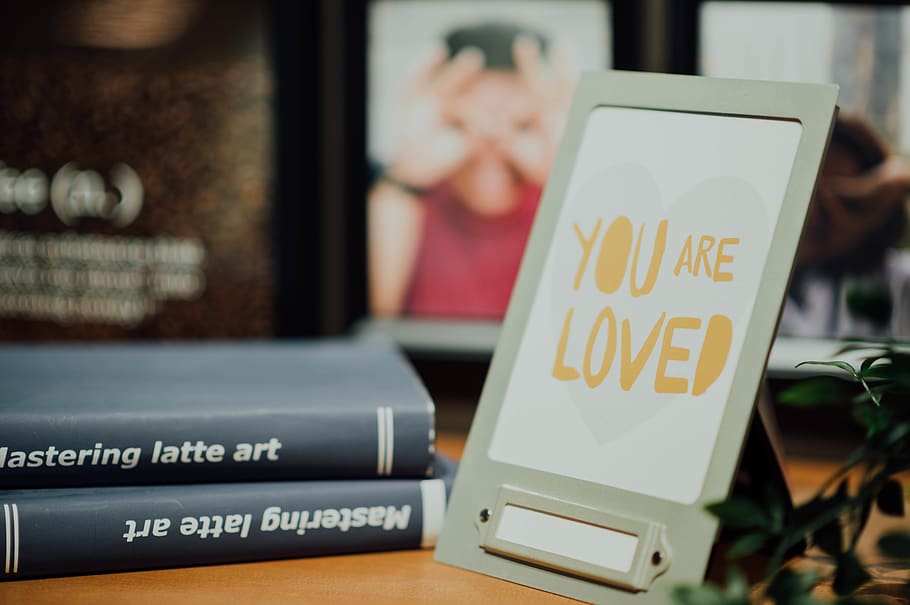 You are loved meesage with gray metal frame on table, person