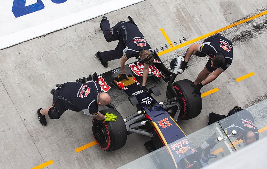 three men at pit stop fixing formula one vehicle, high angle view