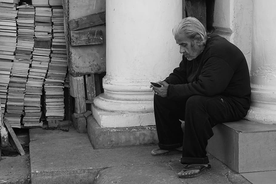 man sitting by the pillar while using smartphone, one person HD wallpaper