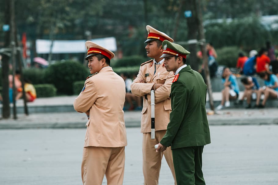 three men in law enforcer uniform standing beside pavement, military