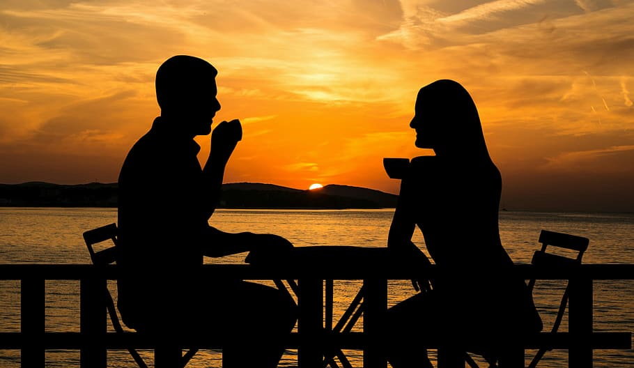 Photo illustration of a couple sitting outside in the sunset, sipping coffee