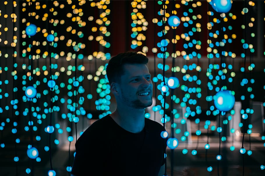 man standing between lighted drop string lights, one person, illuminated HD wallpaper
