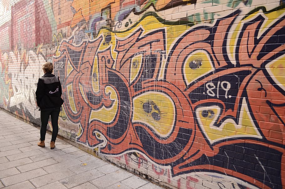 woman walking beside graffiti during daytime, mural, person, human