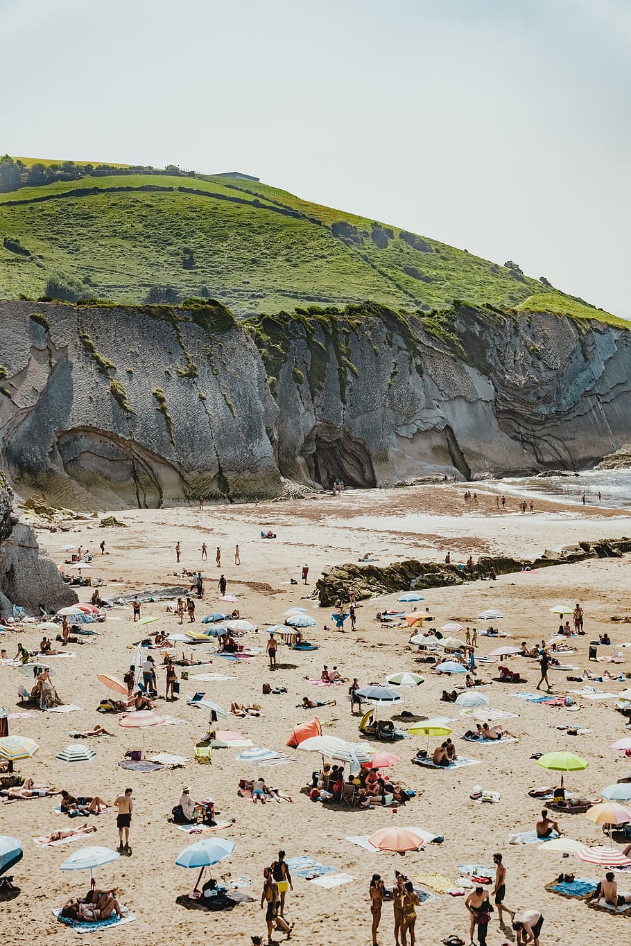 people on beach beside hill during daytime, shore, coast, ridge HD wallpaper