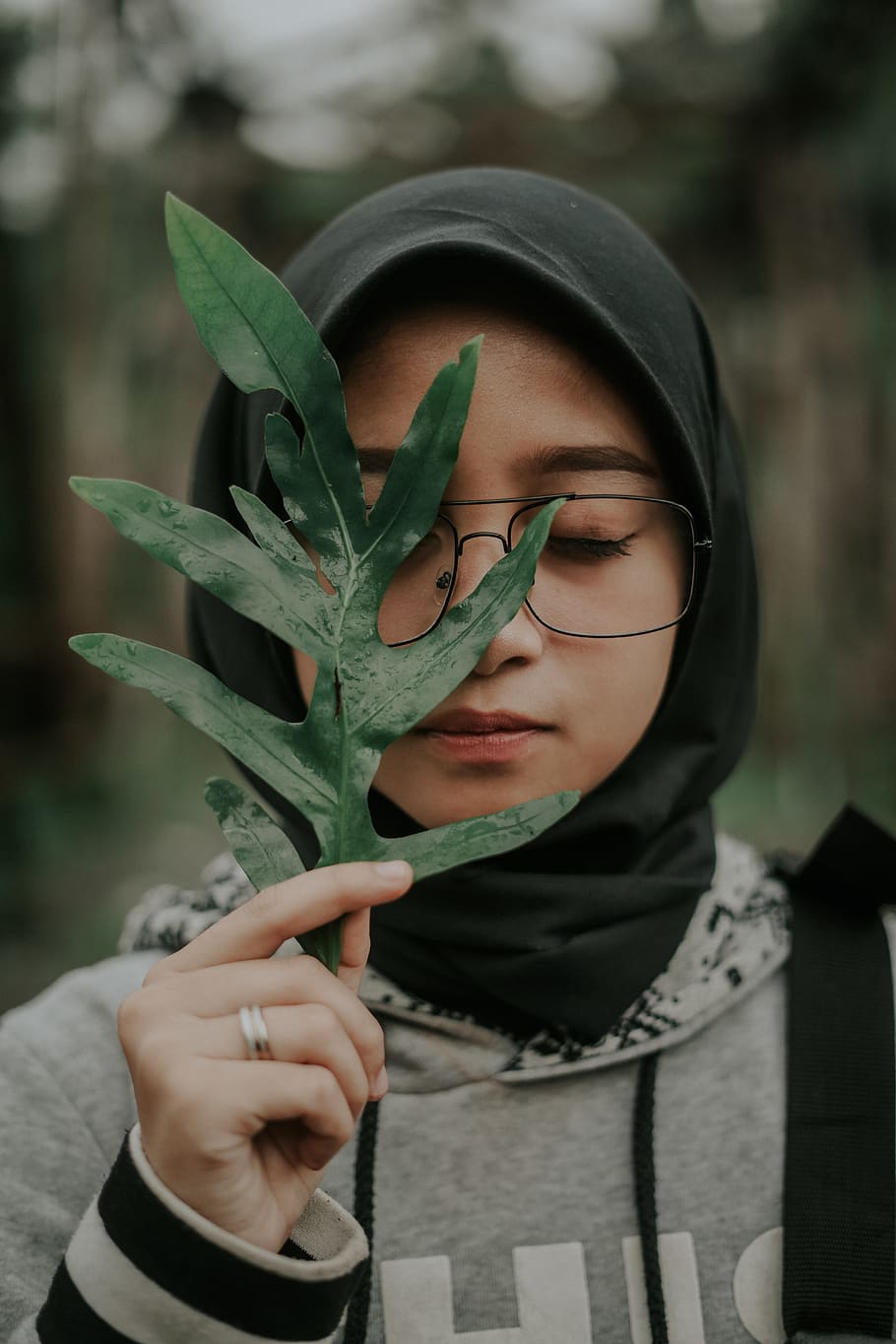 woman wearing hijab holding green leaf, person, human, clothing