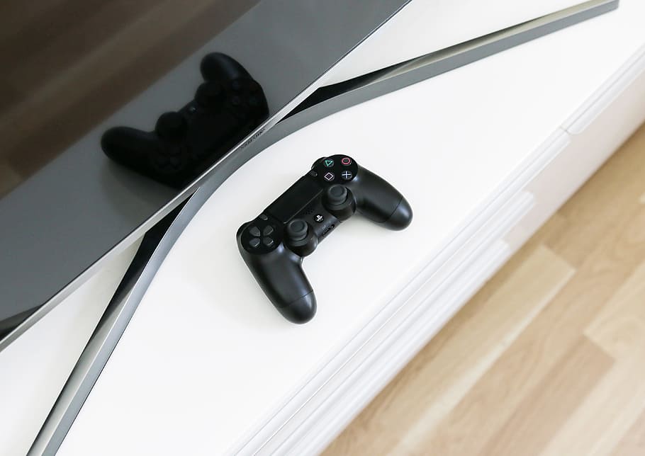 black Sony PS3 controller on white surface, reflection, screen