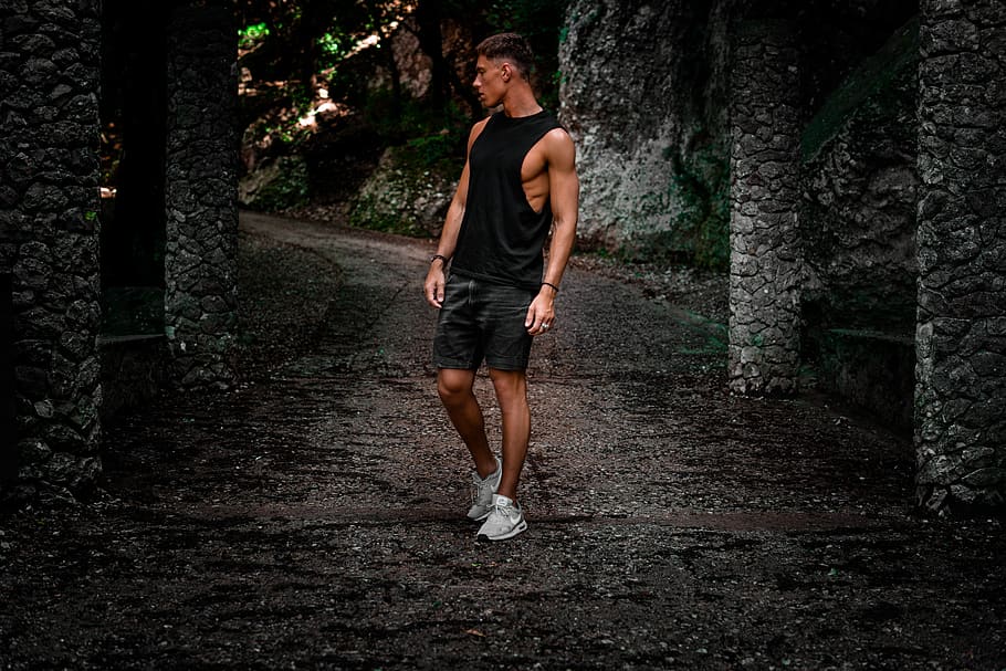 man standing on pathway between concrete post, tree, full length HD wallpaper