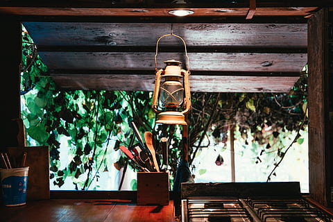 A lantern hung on a forest hut kitchen window over a cutlery holder HD wallpaper