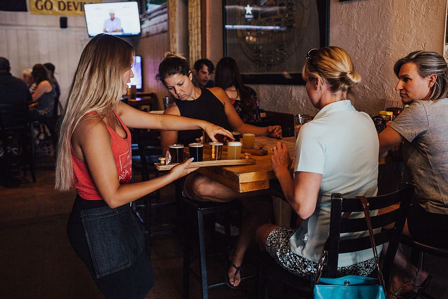 Woman Serving Drinks on Women Sitting Inside an Establishment HD wallpaper