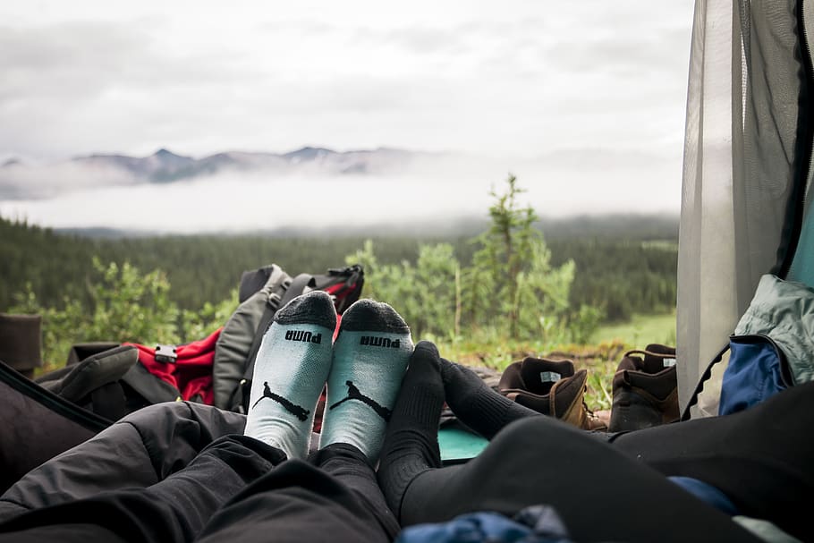 couple laying inside tent in front of mountain view, shoe, clothing