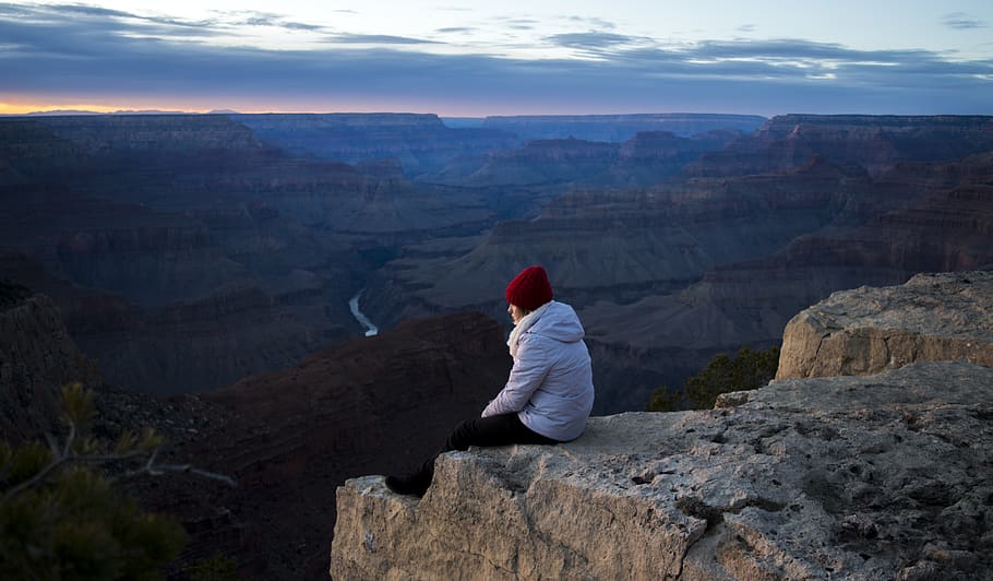 Person Wearing White Hoodie Sitting on Cliff at Daytime, clouds HD wallpaper