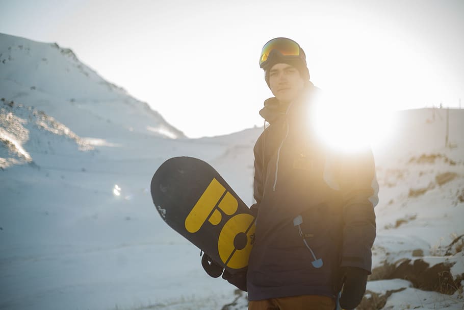 Man in Blue Pullover Hoodie Holding Blue and Yellow Snowboard HD wallpaper