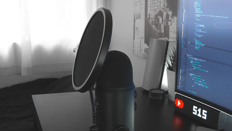 Image of a Blue Yeti microphone sat on a desk with a pop filter attached